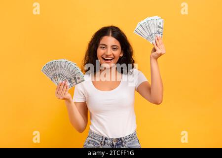 Aufgeregte junge indianerin, die einen Haufen Geldscheine hält Stockfoto