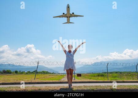 Auf der Straße stehen und ihre Hände in den Himmel zum Flugzeug-One-Mädchen strecken Stockfoto