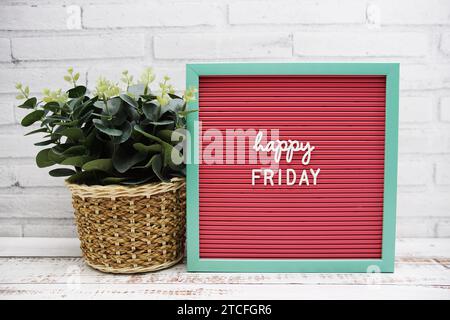 Happy Friday Text auf Letter Board Kunstpflanzen Dekoration auf hölzernem Hintergrund Stockfoto