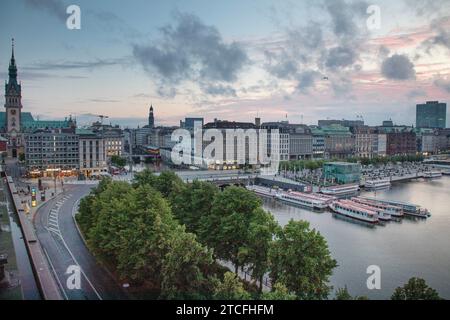 01.07.2023, Hamburg, Hansestadt Hamburg, DE - Blick vom Ballindamm auf die Binnenalster und das Rathaus bei Daemmerung. Abend, Abends, Alster, Ausblick, Ausflugsziel, Aussen, Aussenaufnahme, Aussicht, Ballindamm, beleuchtet, Beleuchtung, Binnenalster, Blaue Stunde, Stadt, Daemmerung, deutsch, Deutschland, Europa, europaeisch, Ferne, Fernsicht, Gebaeude, Gewaesser, Haeuser, Hamburg, Hamburger Rathaus, Hansestadt Hamburg, Horizont, Innenstadt, Jahreszeit, Landschaft, QF, Querformat, Rathaus, Reise, Sommer, Stadt, Stadtansicht, Stadtbild, Stadtlandschaft, Ueberblick, Uebersicht, Wasser, Weitsicht Stockfoto