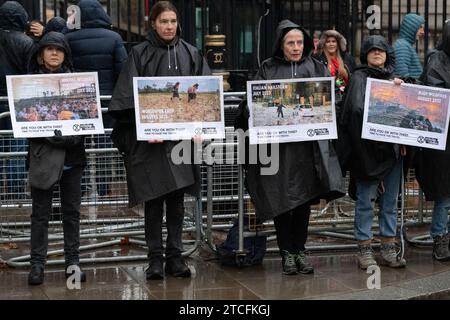 London, Großbritannien. 12. Dezember 2023. Aktivisten der Extinction Rebellion veranstalten eine Mahnwache vor der Downing Street-Residenz des britischen Premierministers Rishi Sunak am letzten Tag der COP 28 UN-Klimakonferenz in Dubai. Fotos von den Auswirkungen extremer Wetterereignisse wie Klimawissenschaftler prognostizieren, werden in Häufigkeit, Dauer und Schwere zunehmen, die eine schrittweise Einstellung der fossilen Brennstoffe fordern, und die Ölindustrie beschuldigen, die COP-Gespräche "einfangen" zu lassen. Quelle: Ron Fassbender/Alamy Live News Stockfoto