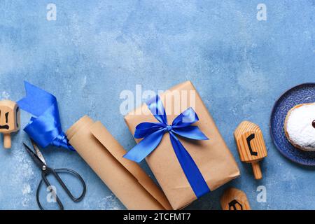 Komposition mit Geschenkbox, Geschenkpapier und Dreidels für Hanukkah Feier farbigen Hintergrund Stockfoto