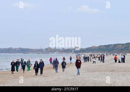 Menschen mit Jacken, die außerhalb der Saison bei kaltem Wetter am Strand von Danzig, Polen, Europa, EU spazieren Stockfoto