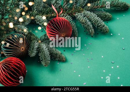 Tannenspielzeug und Zweige mit goldenem Konfetti auf grünem Hintergrund. Weihnachtskonzept. Draufsicht, flach, Kopierbereich. Stockfoto