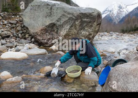 Outdoor-Abenteuer auf dem Fluss. Goldwaschen, Suche nach Gold im Winter. Der Mann sucht Gold in einem Bergbach Stockfoto