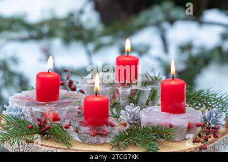 Adventsarrangements mit roten Kerzen, Eisfiguren, Hagebutten und Tannenzweigen Stockfoto