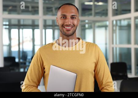 Schöner glücklicher Mann mit Laptop im Büro Stockfoto