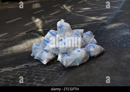 Ein Haufen weißer Müllsäcke mit blauen Markierungen auf der Straße und dem Bürgersteig im Stadtzentrum von Brüssel Stockfoto