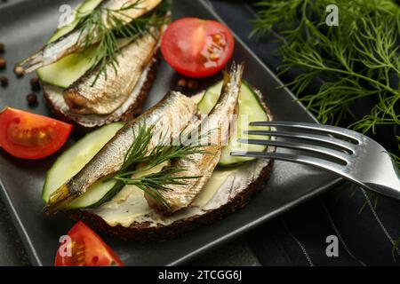 Köstliche Sandwiches mit Sprats, Gurke und Dill auf Teller serviert, Nahaufnahme Stockfoto