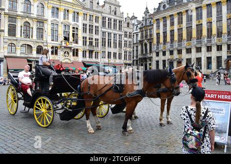 Kutsche mit Pferd, die Touristen am Grand Place im mittelalterlichen Stadtzentrum von Brüssel für eine Besichtigungstour abholt Stockfoto