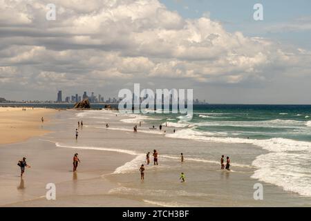 Australier Touristen an einem Gold Coast Beach mit der City Skyline im Hintergrund Stockfoto