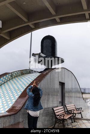 Das junge Mädchen grüßt das religiöse hindusymbol Shivalinga mit Wasser, das morgens fließt Stockfoto