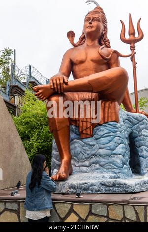 Ein junges Mädchen, das morgens aus flachem Winkel der Statue des hindugottes shiva grüßt, wird an der Statue des Glaubens nathdwara rajasthan india aufgenommen. Stockfoto