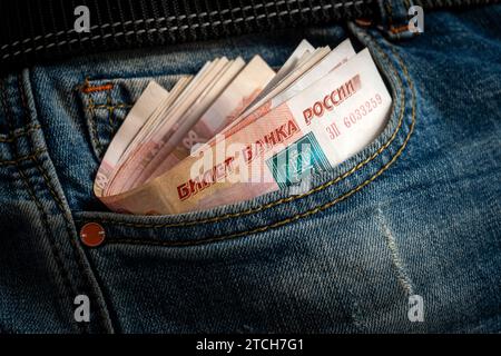 Geld in der Tasche der blauen Jeans. Aus der Tasche der blauen Jeans ragt ein großer Schwarm russischer Tausend Rubel-Scheine hervor. Stockfoto