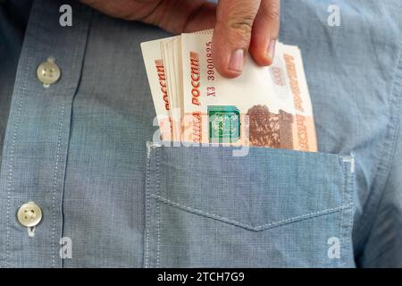 Hände nehmen russische Rubel aus der Tasche. Nahaufnahme der Hände eines Mannes, während er eine Banknote aus seiner Tasche holt. Viel Geld. Ein reicher Mann. Einkommen Stockfoto