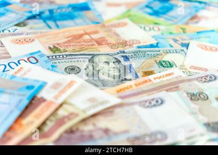 100-Dollar-Schein unter etwa fünftausend Rubel-Banknoten. Nahaufnahme. Währungsumtauschkonzept. Stockfoto