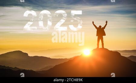 2025. Neujahr 2025, Neubeginn Motivation inspirierende Zitat-Botschaft auf Silhouette des Siegermannes bei Sonnenuntergang mit erhobenen Armen im Glück. Willkommen Happy n Stockfoto