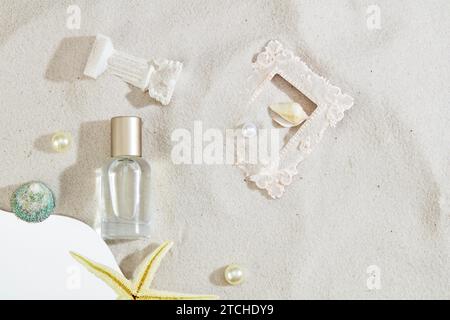 Eine Parfümflasche ohne Marke, die mit Muscheln, Perlen und Ornamenten auf sandigem Hintergrund verziert ist. Ein frisches, lebendiges Sommererlebnis. Draufsicht elegan Stockfoto
