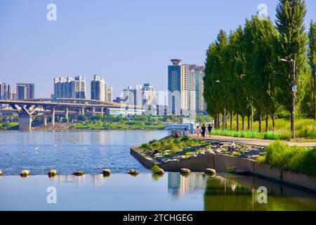 Seoul, Südkorea - 2. Juni 2023: Eine ruhige Darstellung des ruhigen Wassers von Tan Stream vor dem Eintritt in den Han River, mit Parkbesuchern auf Pfaden entlang der Emb Stockfoto