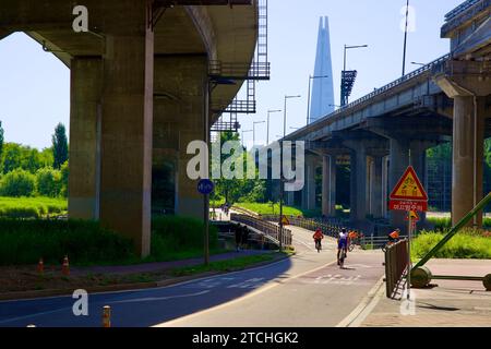 Seoul, Südkorea - 2. Juni 2023: Radfahrer überqueren eine Brücke über den Tan Stream mit dem hoch aufragenden Olympic Boulevard und der berühmten Lotte World Stockfoto