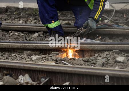 Details mit einem Arbeiter, der eine Oxy-Acetylen-Taschenlampe zum Schneiden von Straßenbahnschienen aus Metall verwendet. Stockfoto
