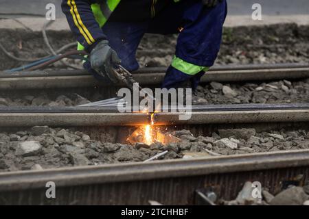 Details mit einem Arbeiter, der eine Oxy-Acetylen-Taschenlampe zum Schneiden von Straßenbahnschienen aus Metall verwendet. Stockfoto