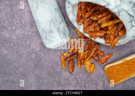 Ganze Cayennepfeffer in einem weißen Marmormörtel und gemahlener Cayennepfeffer in einem Holzlöffel Stockfoto