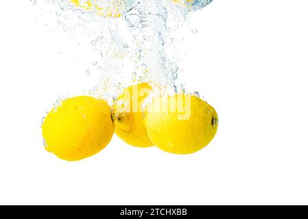 Zitronen spritzen ins Wasser und sinken auf weißem Hintergrund. Leckere und gesunde Lebensmittel Stockfoto