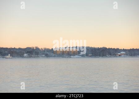 Gelbes Schulgebäude des Campus Manilla, bedeckt mit weißem Schnee am Djurgården in Stockholm, Schweden, im Winter am frühen hellen Morgen Stockfoto