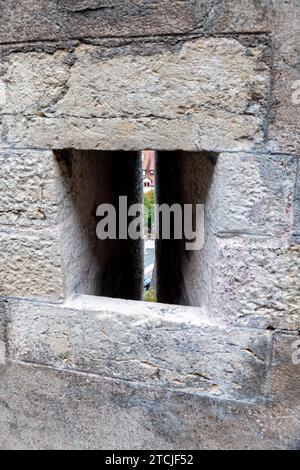 Ein Embrasure in einer dicken alten Mauer mit einem langen, schmalen vertikalen Schlitz, durch den Bogenschützen ihre Waffen im Mittelalter abfeuerten. Stockfoto