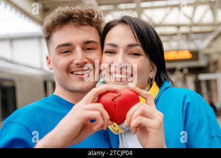 Ein Paar schließt sich an und hält ein rotes gebrochenes Herz. Treffen nach einem Trennungskonzept Stockfoto