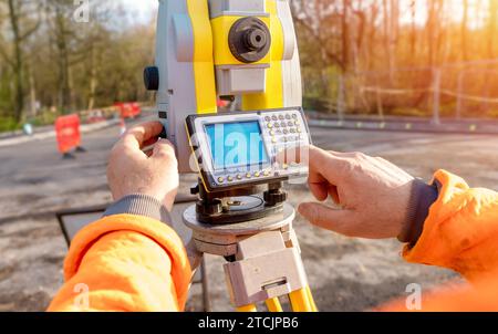 Bauingenieur, der sein Gerät bei Bauarbeiten bedient. Bauherr verwendet Tachymeter für die Gesamtpositionierung auf der Baustelle für neue Straßeneinstellungen Stockfoto