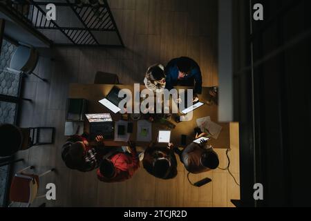 Mitarbeiter aus mehreren Generationen arbeiten in einem späten Büro zusammen und diskutieren Geschäftsstrategien für Projektabschluss und Gewinnwachstum. Stockfoto