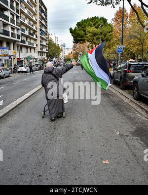 Marseille, Frankreich. Dezember 2023. Eine ältere Palästinenserin mit Walker läuft allein vor der Demonstration und schwenkt eine palästinensische Flagge. Die Demonstration für einen Waffenstillstand im Gazastreifen fand nach einer Entscheidung des Verwaltungsgerichts zunächst vom Polizeipräsidium Bouches-du-RhÃ wegen ernsthafter Gefahr einer Störung der öffentlichen Ordnung verboten statt. Die Demonstration für einen Waffenstillstand im Gazastreifen fand nach einem Beschluss der Verwaltung zunächst vom Polizeipräsidium Bouches-du-RhÃ wegen ernsthafter Gefahr einer Störung der öffentlichen Ordnung verboten statt Stockfoto