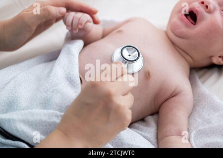 Hand hält Stethoskop an der Brust des Neugeborenen Stockfoto