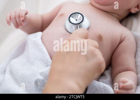 Hand hält Stethoskop an der Brust des Neugeborenen Stockfoto