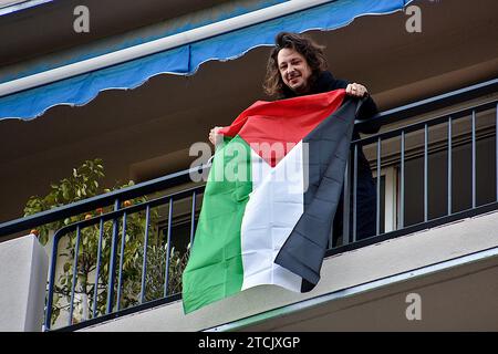 Marseille, Frankreich. Dezember 2023. Ein Bewohner auf seinem Balkon schwingt eine palästinensische Flagge, während die Demonstration vorbeigeht. Die Demonstration für einen Waffenstillstand im Gazastreifen fand nach einer Entscheidung des Verwaltungsgerichts zunächst vom Polizeipräsidium Bouches-du-RhÃ wegen ernsthafter Gefahr einer Störung der öffentlichen Ordnung verboten statt. (Credit Image: © Gerard Bottino/SOPA Images via ZUMA Press Wire) NUR REDAKTIONELLE VERWENDUNG! Nicht für kommerzielle ZWECKE! Stockfoto