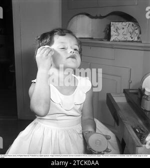 In den 1950er Jahren Ein kleines Mädchen schminkt sich und benutzt ein Puder im Gesicht. 1956. Kristoffersson Ref. BS96-11 Stockfoto