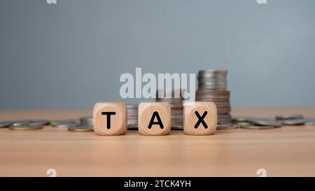 Druckbildschirm mit Steuertext auf Holzwürfelblock und Münzen stapeln für Steuerwachstum und Planungskonzept, Steuersätze zahlen, Steuern erheben. Stockfoto