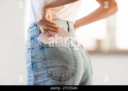 Nahaufnahme einer Dame, die Menstruationspad in die Jeanstasche gesteckt hat Stockfoto