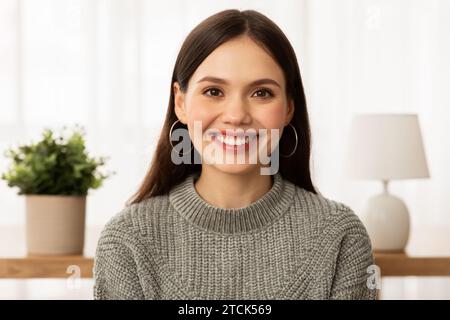 Hübsche junge Brünette, die legere Kleidung trägt und zu Hause posiert Stockfoto