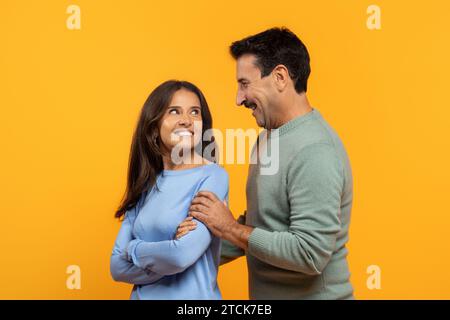 Zwei fröhliche ältere Männer und Frauen teilen sich einen unbeschwerten Moment, lachen und schauen sich gegenseitig an Stockfoto