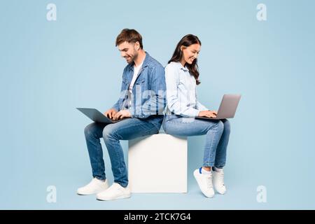 Ein Paar, das sich auf Cube konzentriert und Laptops in Denim-Kleidung verwendet Stockfoto