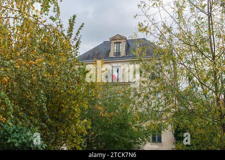 Paris, Frankreich, 2023. Die Fassade der Bibliothèque de l'Arsenal, gesehen durch das gelbliche Laub der Bäume im Jardin Teilhard de Chardin Stockfoto