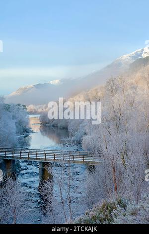 Glen Affric Cannich Schottland am frühen Wintermorgen mit Nebel über der Flussbrücke und schneebedeckten Bergen Stockfoto