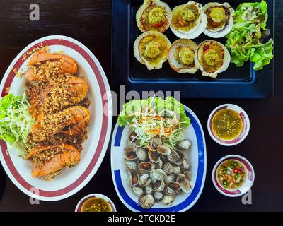 Blick von oben auf Variety Seafood Partytisch mit Jakobsmuscheln, Cockle, Krabben, Muscheln, Garnelen, Flusskrebse auf schwarzem Hintergrund. Meeresfrüchte-Platte auf schwarzem Holztisch Stockfoto