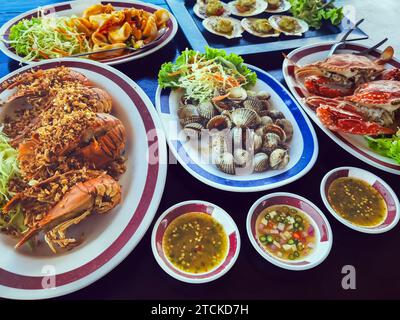 Blick von oben auf Variety Seafood Partytisch mit Jakobsmuscheln, Cockle, Krabben, Muscheln, Garnelen, Flusskrebse auf schwarzem Hintergrund. Meeresfrüchte-Platte auf schwarzem Holztisch Stockfoto