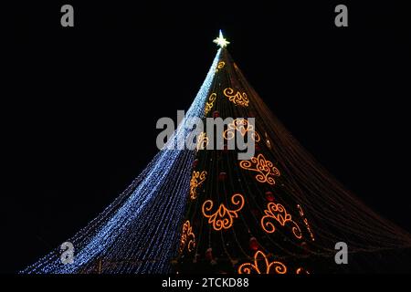 Festlicher Weihnachtsbaum mit bunten Ornamenten auf schwarzem Hintergrund Stockfoto