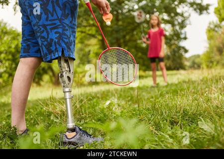 Niedriger Teil eines Jungen mit amputiertem Bein, der Badminton im Park spielt Stockfoto