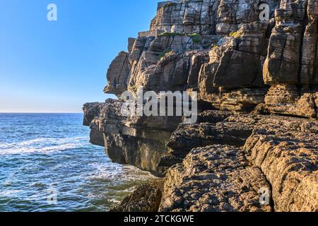 Wunderschöne Klippen und Felsformationen in Peniche, Portugal, an sonnigen Tagen. Verwitterte Felsformationen, geologisches Interesse, Klippen, blaue Meereswellen, Gezeiten, Küste, klarer blauer Himmel Stockfoto